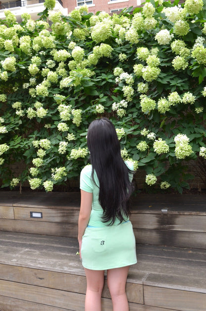 Model wearing Nel set back view, mint mock-neck shirt and mini skirt, Espada collection