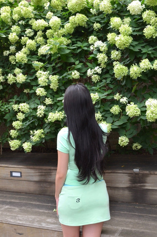 Model wearing Nel set back view, mint mock-neck shirt and mini skirt, Espada collection